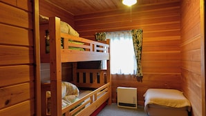 A wooden cabin room with bunk beds, a small table, and a heater. - Plaisir (Suzaka)