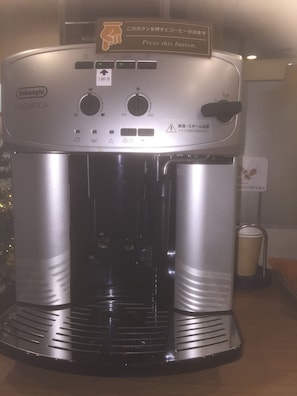 A Delonghi Magnifica coffee machine with control knobs, a button, and a coffee pot.