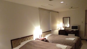 A hotel room with two beds, a desk with a computer, a lamp, and a mirror on the wall. - Hotel Green Park (Sendai)