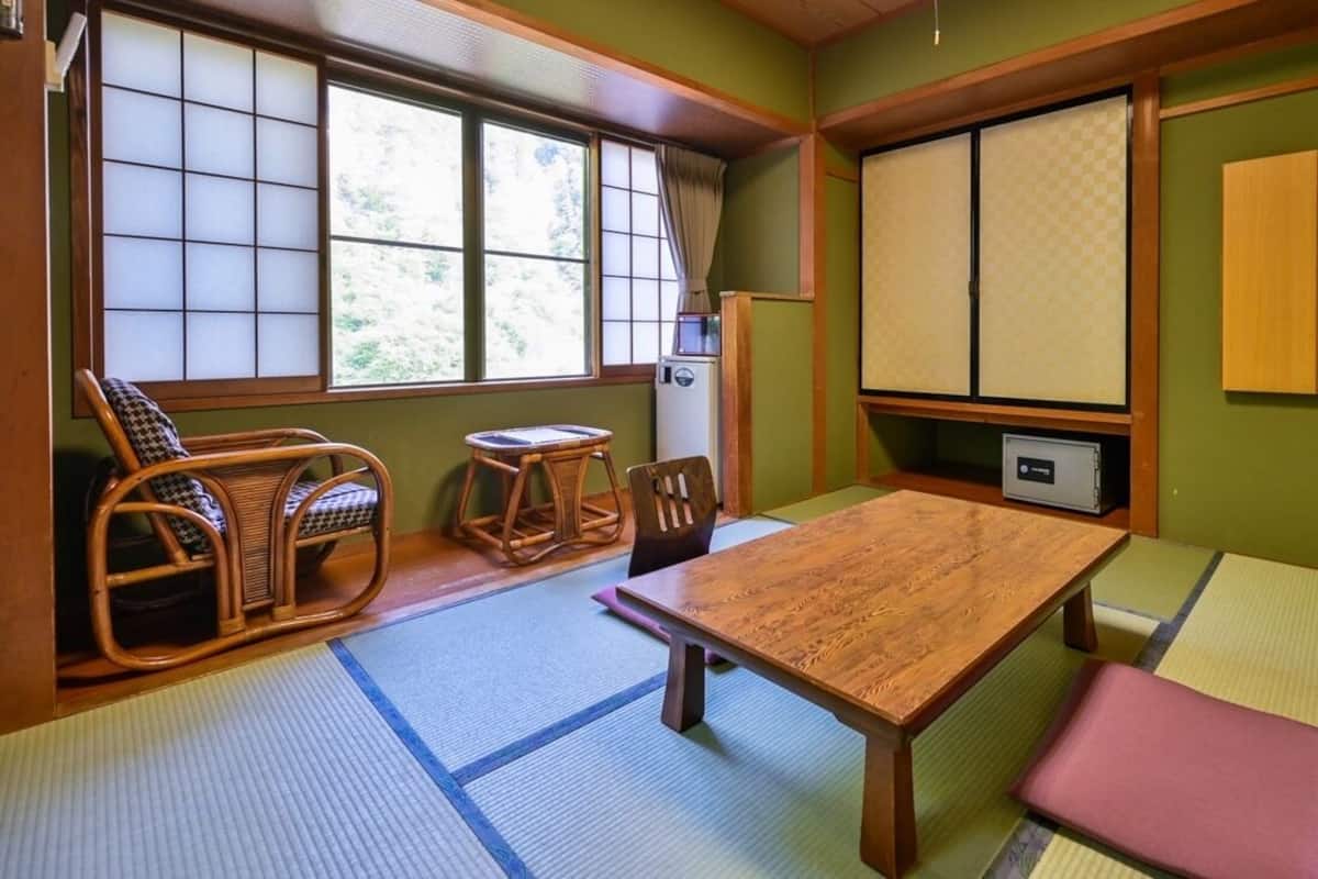 A traditional Japanese room with tatami flooring, a low wooden table, and a seating area with a low wooden table and chairs.