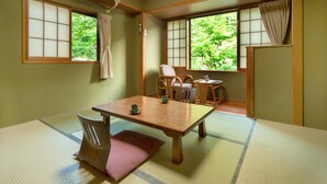 Une pièce de style japonais traditionnel, avec un sol recouvert de tatamis, une table basse et un coin salon comprenant une chaise et une petite table.