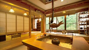 Une pièce de style japonais traditionnel, avec un sol recouvert de tatamis, une sculpture de poisson suspendue et une vue sur la verdure à l’extérieur.