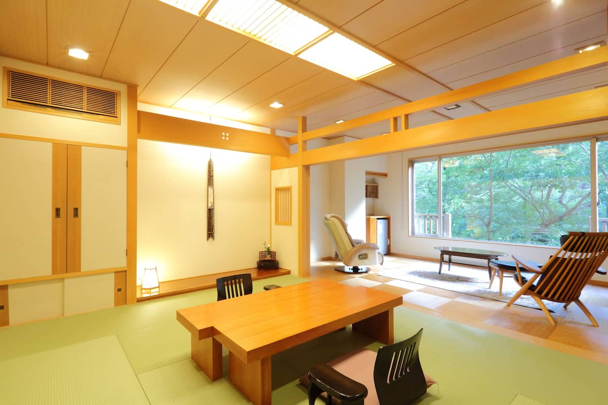 A traditional Japanese-style room with tatami flooring, a wooden dining table, and a view of the outdoors.