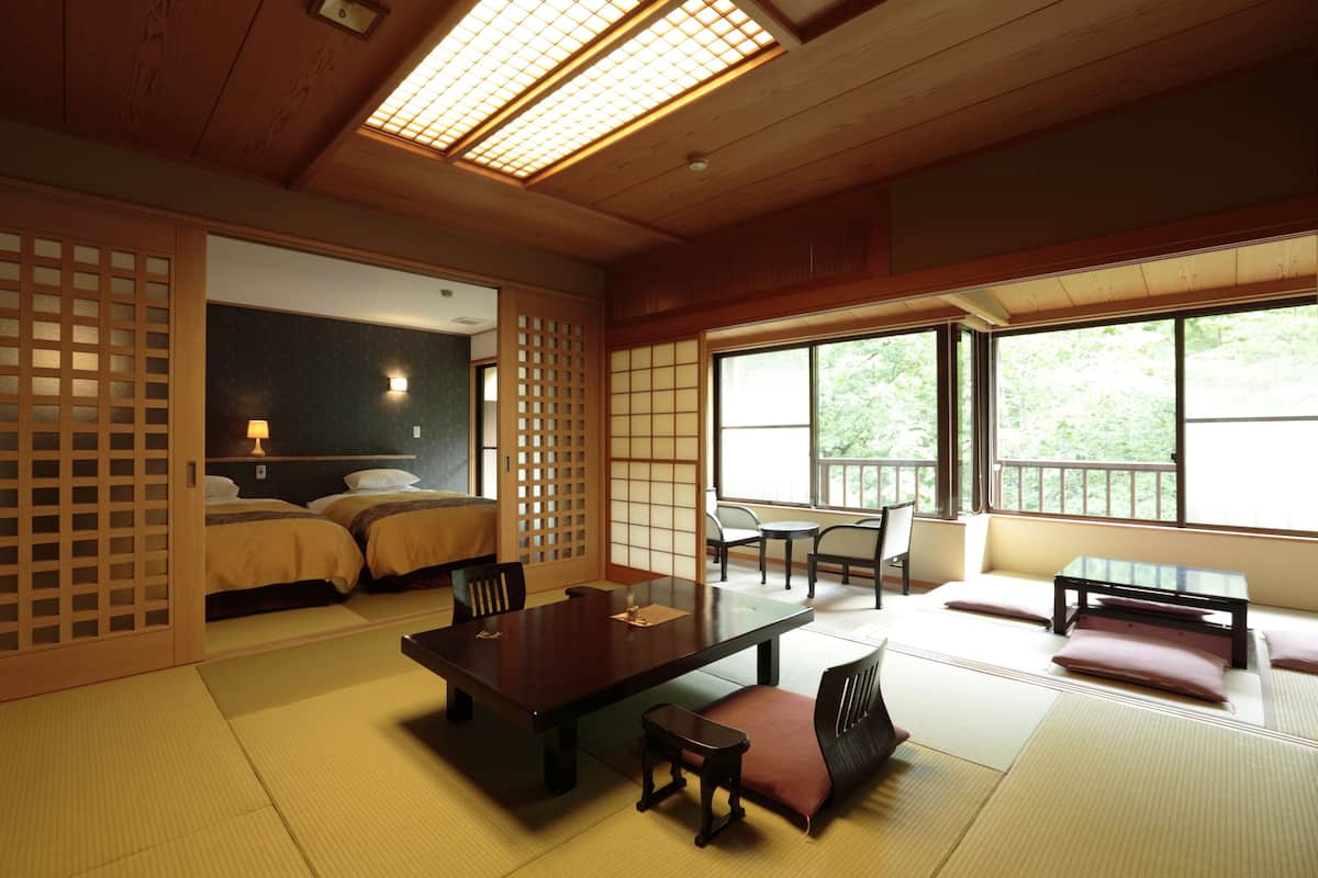 A traditional Japanese room with tatami flooring, a low table, and a sliding door.