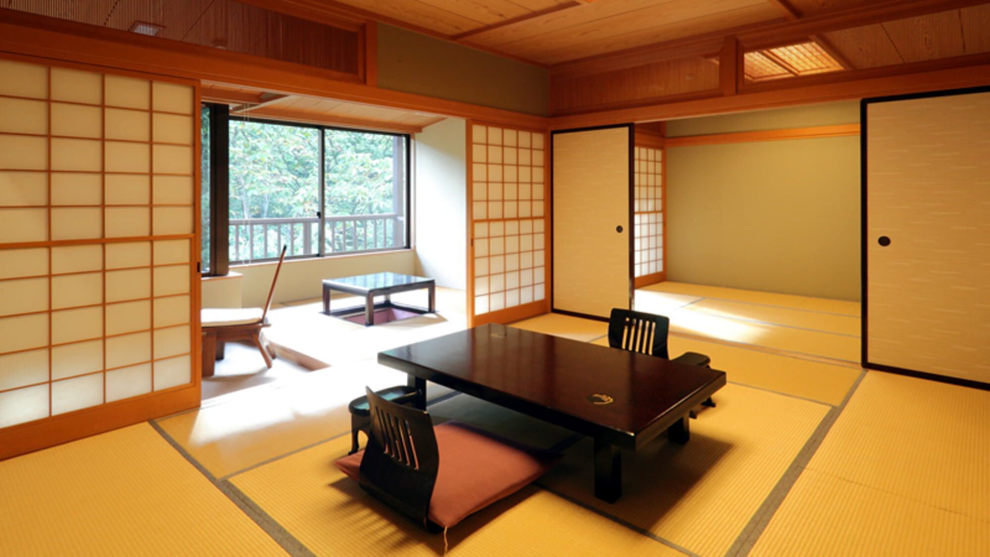 Una habitación con esteras de tatami, una mesa baja, sillas y una puerta corredera.