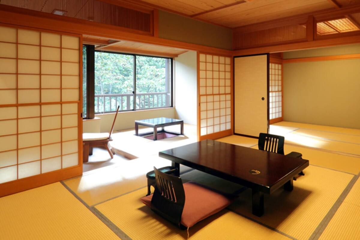 Una habitación con esteras de tatami, una mesa baja, sillas y una puerta corredera.