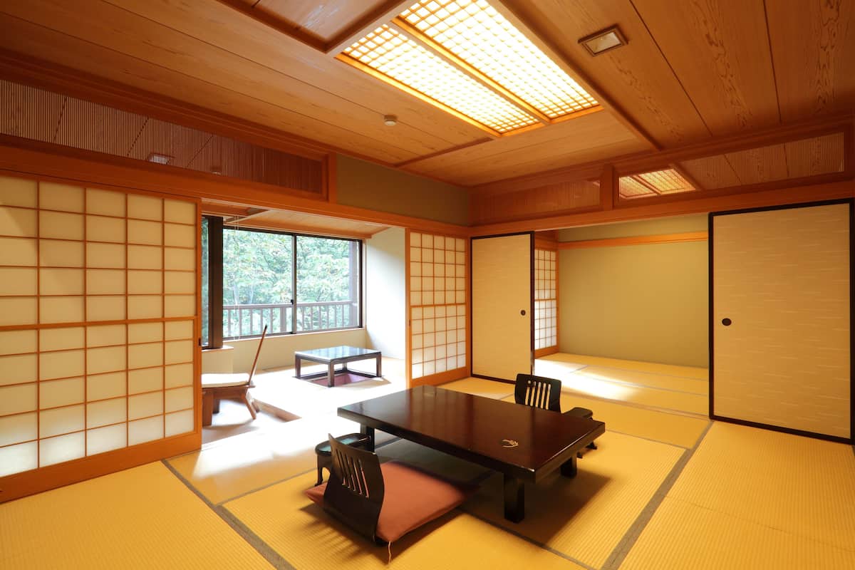 A traditional Japanese room with tatami flooring, a low table, and sliding doors.