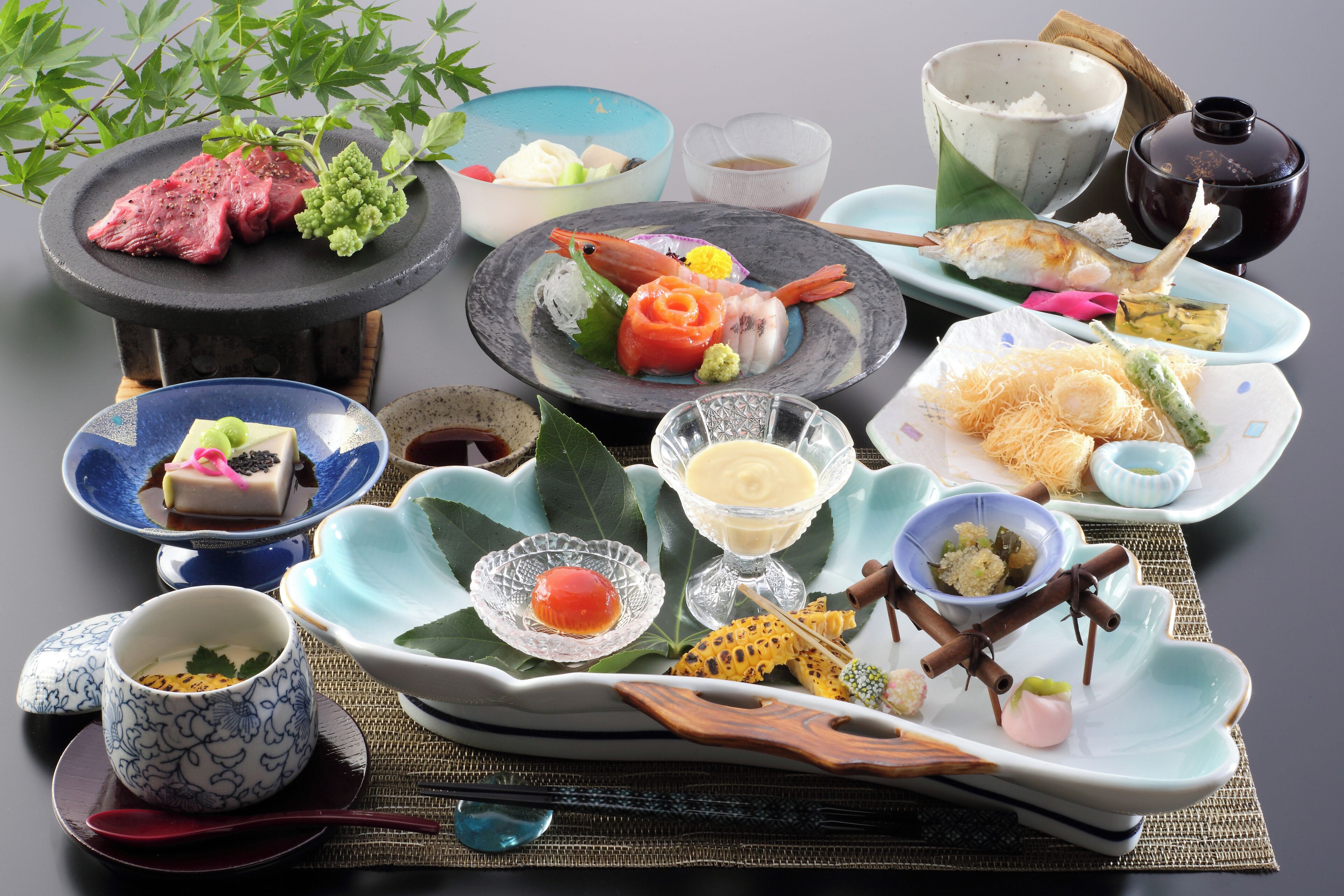 On peut voir une variété de plats et d’ustensiles sur une table, notamment un bol de riz, une assiette de poisson et une tasse avec une cuillère.