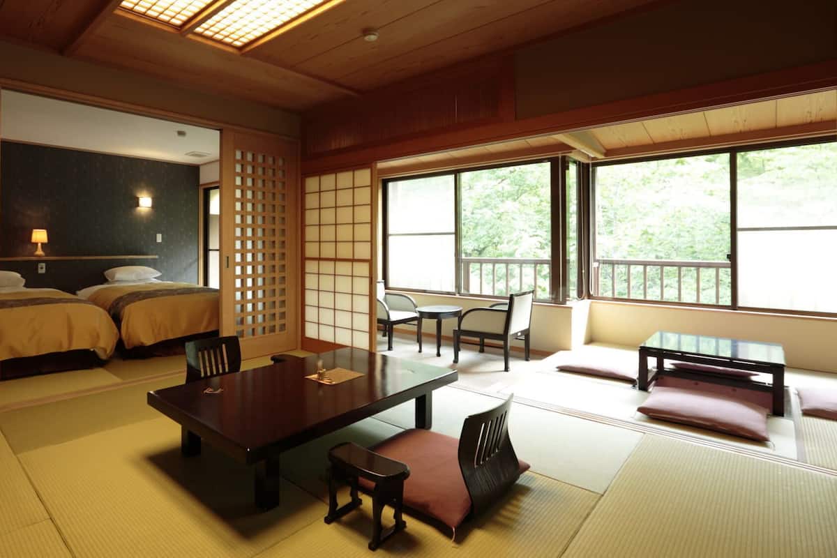 Perinteinen japanilaistyylinen huone, jossa on tatamimatto, matala pöytä tyynyineen ja liukuovi.