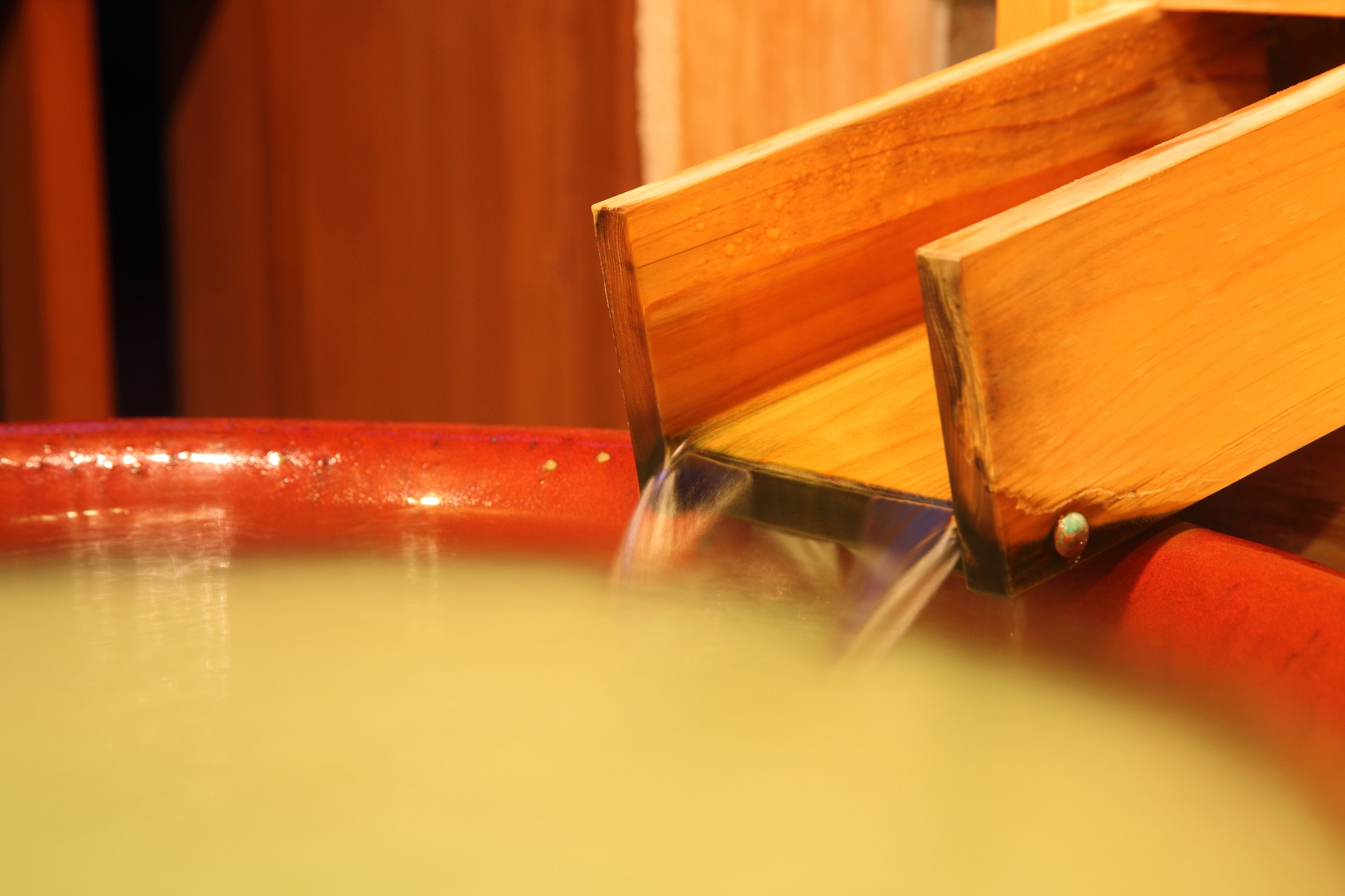 A wooden chair with a metal frame partially submerged in a yellow liquid.