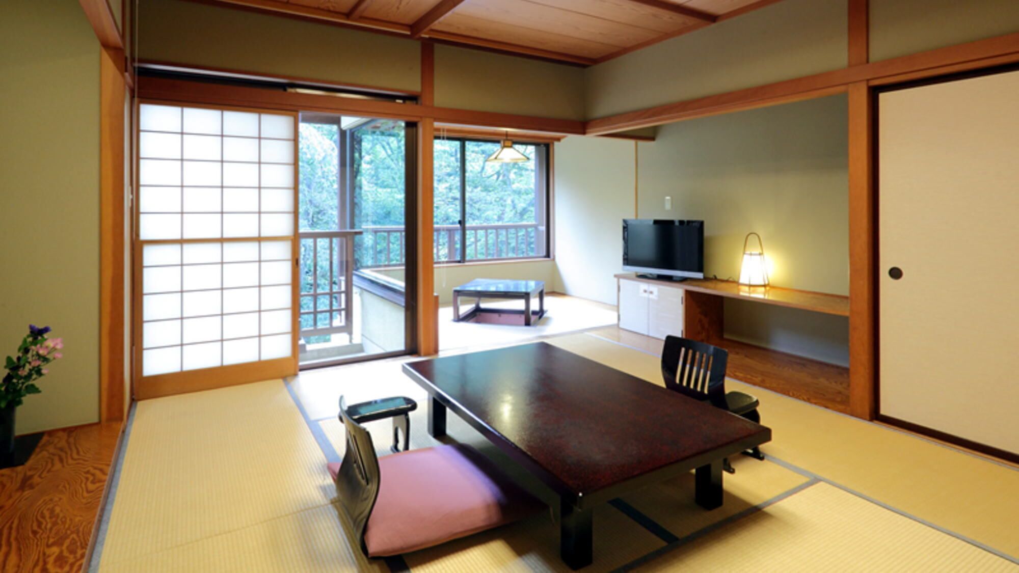 A tatami mat room with a low table, a chair, a television, and a cabinet.