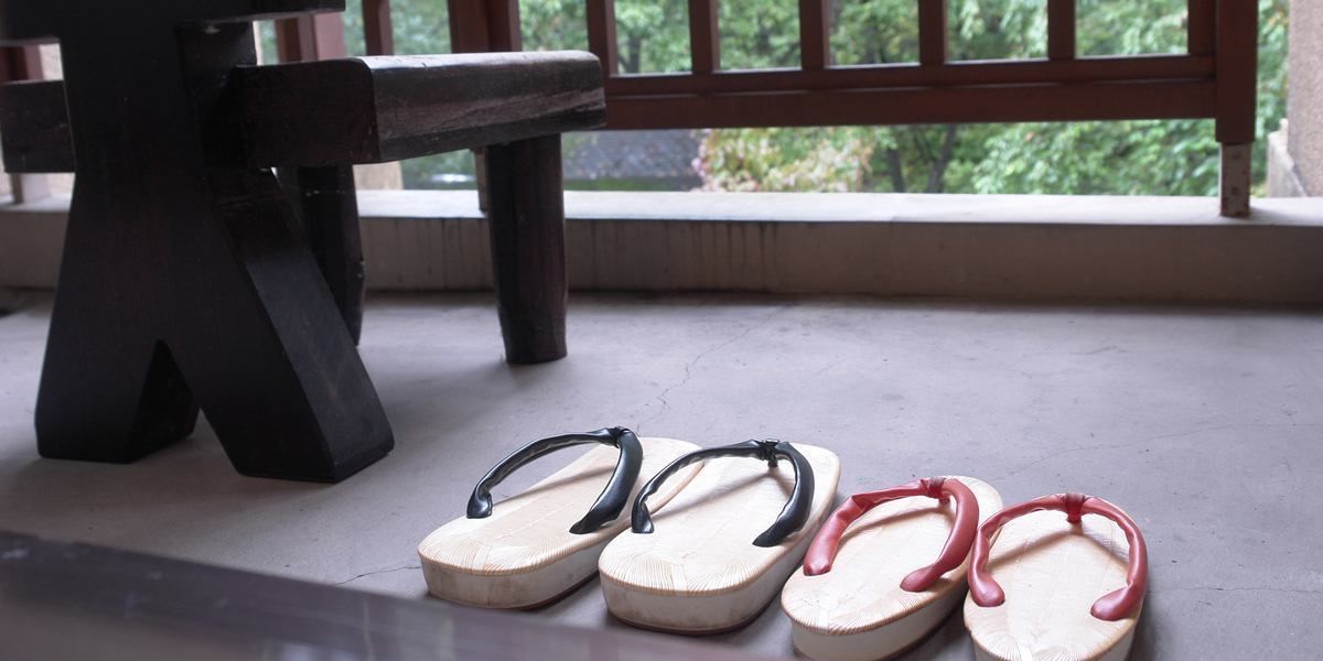 Un par de chanclas sobre un suelo de hormigón cerca de una ventana con vistas a zonas verdes.