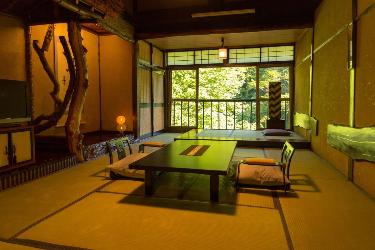 Um quarto japonês tradicional com tatames, uma mesa baixa e almofadas.