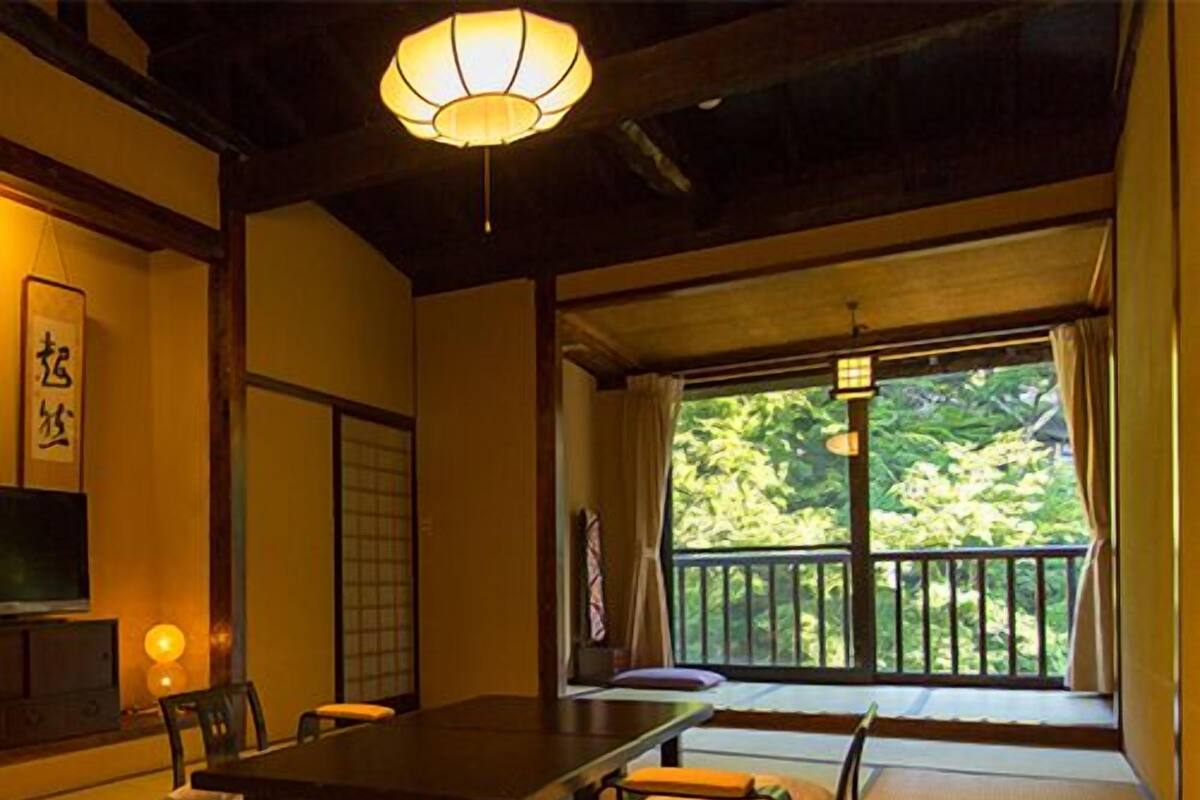 Quarto japonês tradicional com tatames, uma mesa baixa e vista para o verde lá fora.