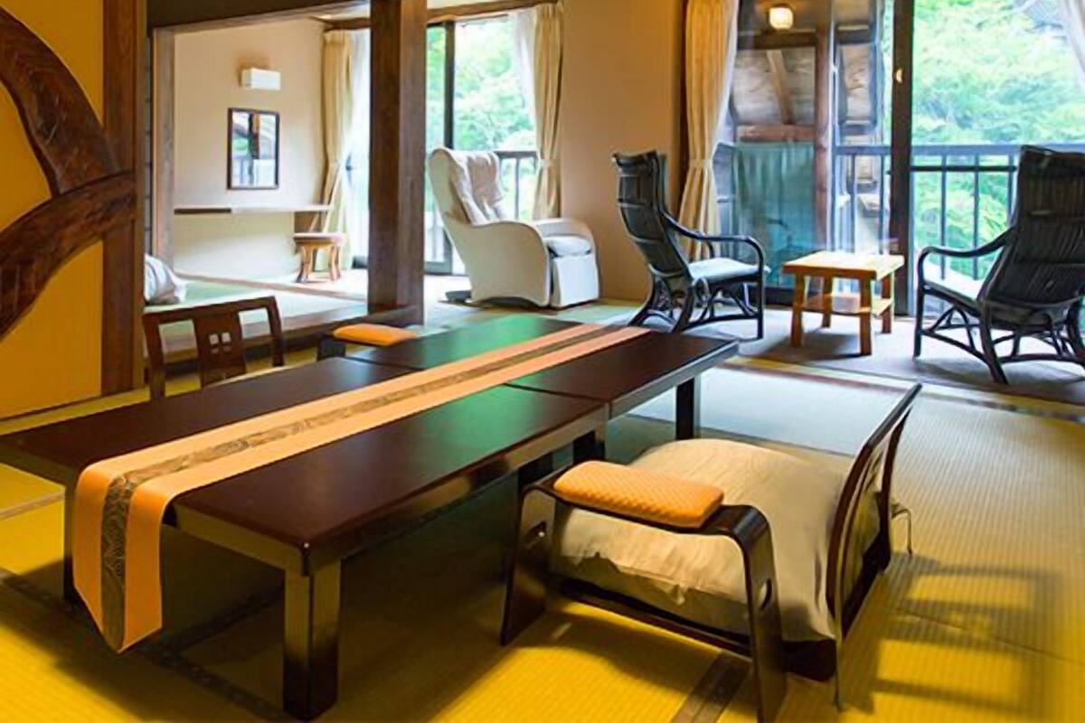 Quarto tradicional japonês com tatames, uma mesa baixa e vista para o verde lá fora.