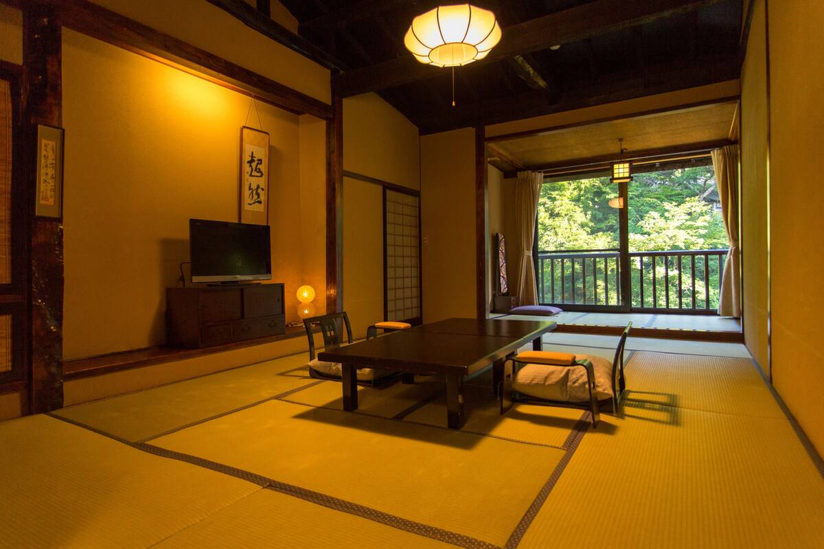 Um quarto japonês tradicional com tatames, uma mesa baixa e cadeiras.