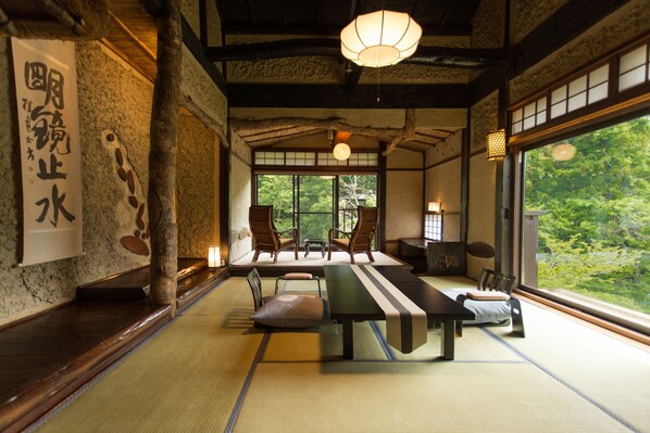 A traditional Japanese room with tatami flooring, a low table, and chairs.