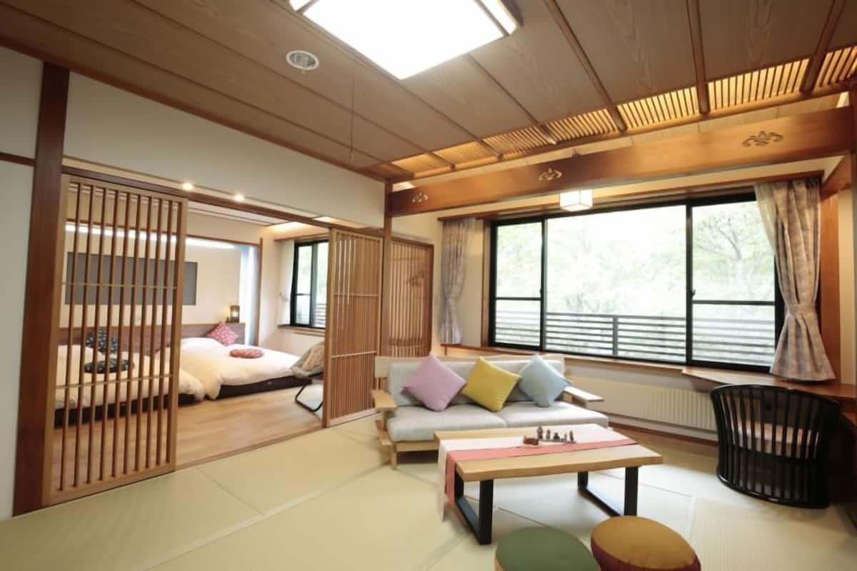 Een traditionele Japanse kamer met tatami vloerbedekking, een lage tafel, een bank met kussens en een schuifdeur.