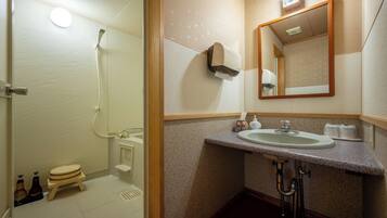 Une salle de bain équipée d’une douche, de toilettes, d’un lavabo et d’un miroir.