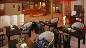 A spacious indoor area with multiple tables and chairs, a reception desk, and a red umbrella. - Zao Onsen Kinosato (Yamagata)