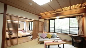 A traditional Japanese-style room with tatami flooring, a low table, a sofa with cushions, and a sliding door. - Zao Onsen Kinosato (Yamagata)