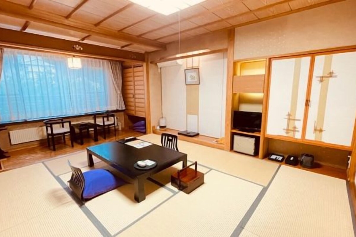 Une pièce de style japonais traditionnel, avec un sol recouvert de tatamis, une table basse et des portes coulissantes.