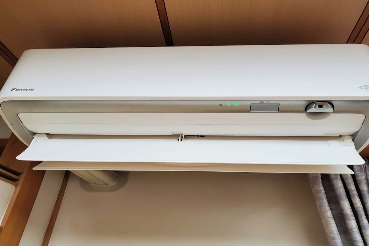 Een witte Daikin airconditioner met bedieningspaneel en een stopcontact.
