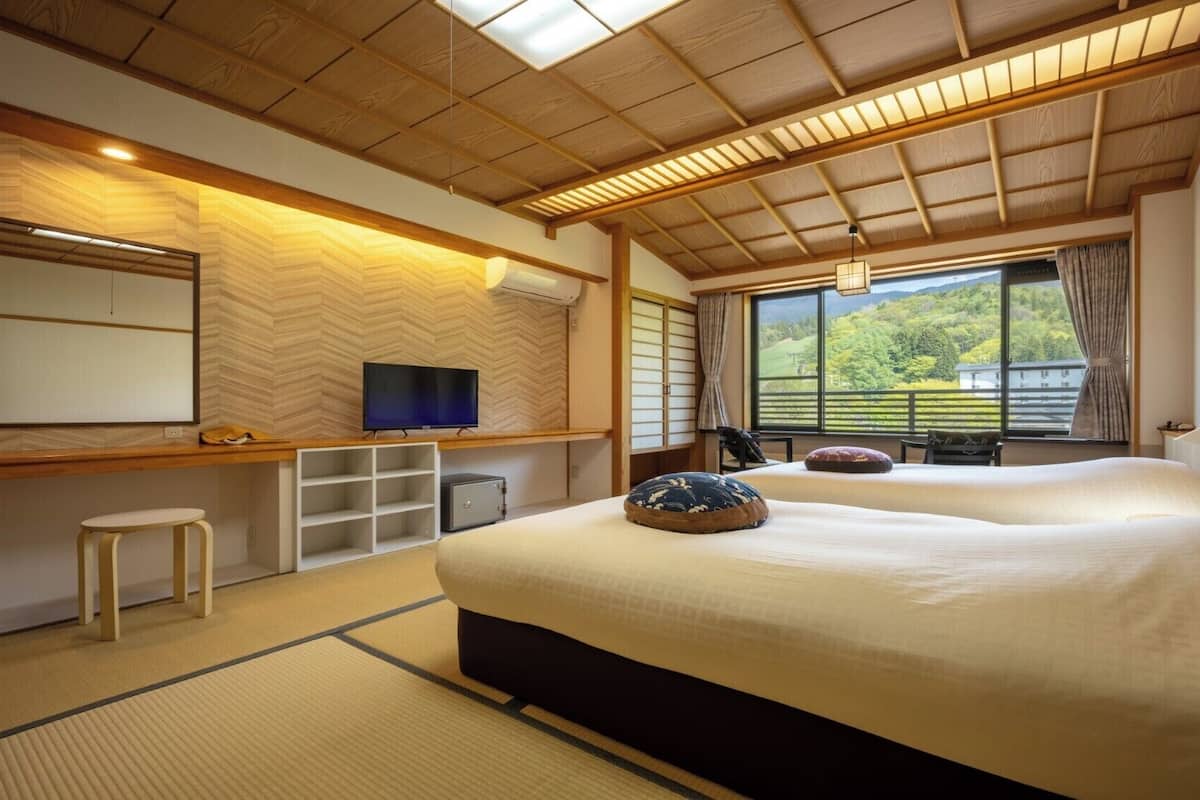Hotelkamer met een groot bed, een televisie, een bureau met stoel en uitzicht op groen.