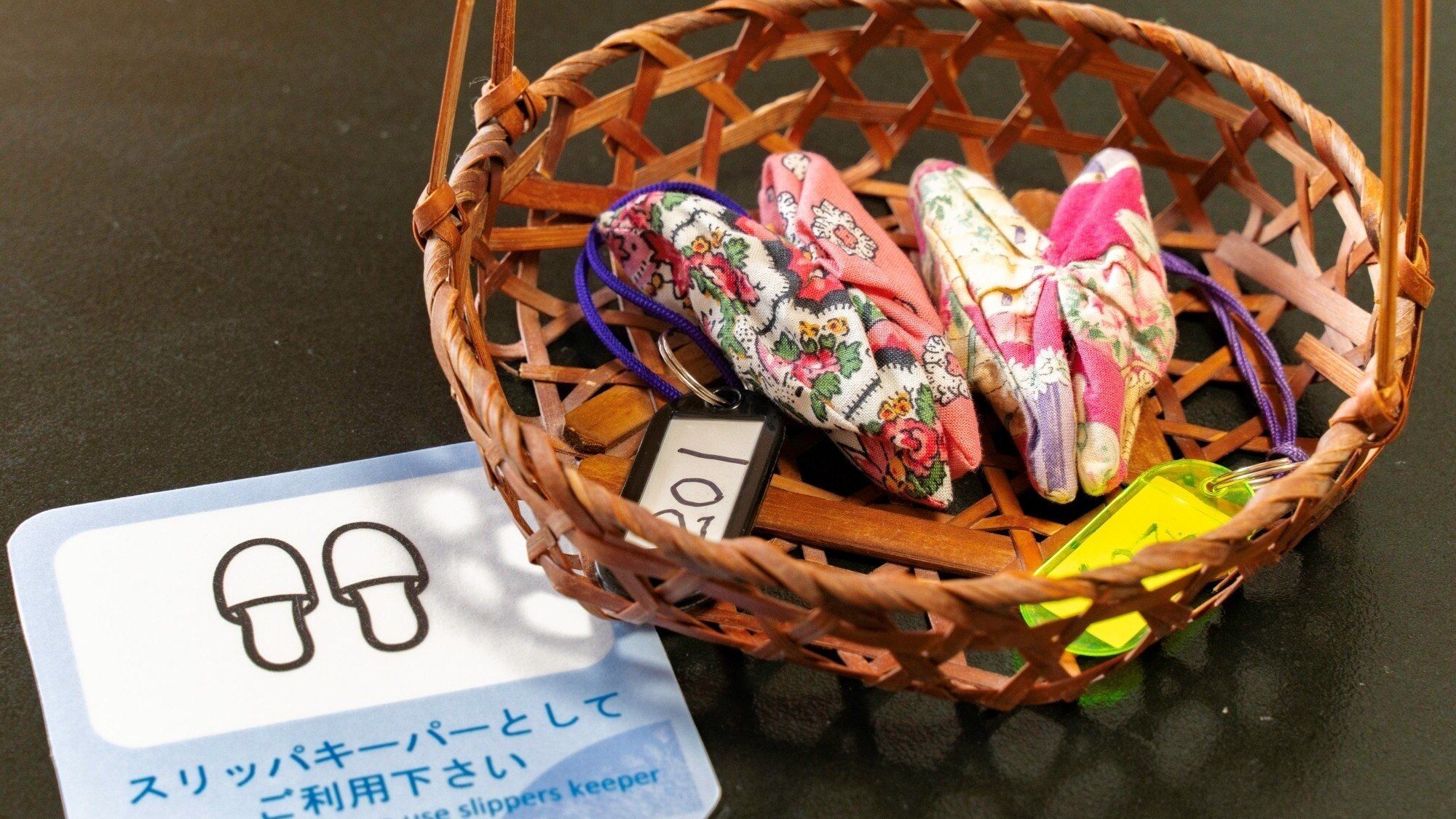Una cesta con zapatillas y una tarjeta con texto en japonés.