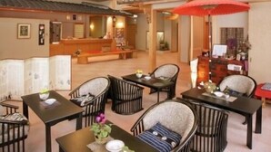 A hotel lobby with a reception desk, seating area with chairs and tables, and a red umbrella. - Zao Onsen Kinosato (Yamagata)