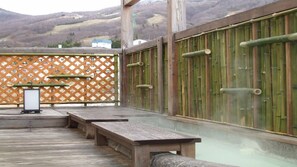 Une terrasse en bois avec des bancs, une clôture en bois et un mur en bambou.
