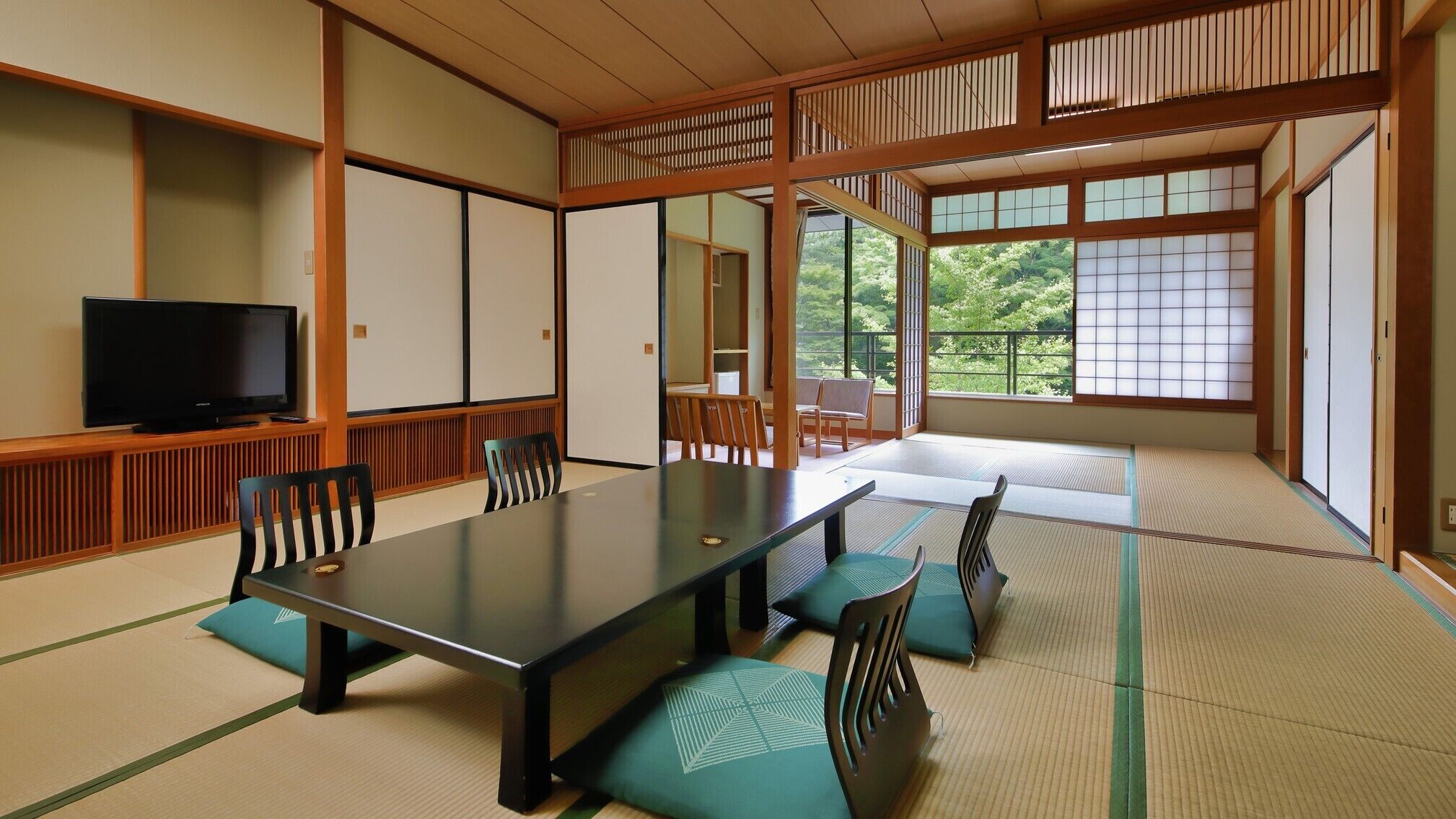 A traditional Japanese-style room with tatami flooring, a low table, and a television.