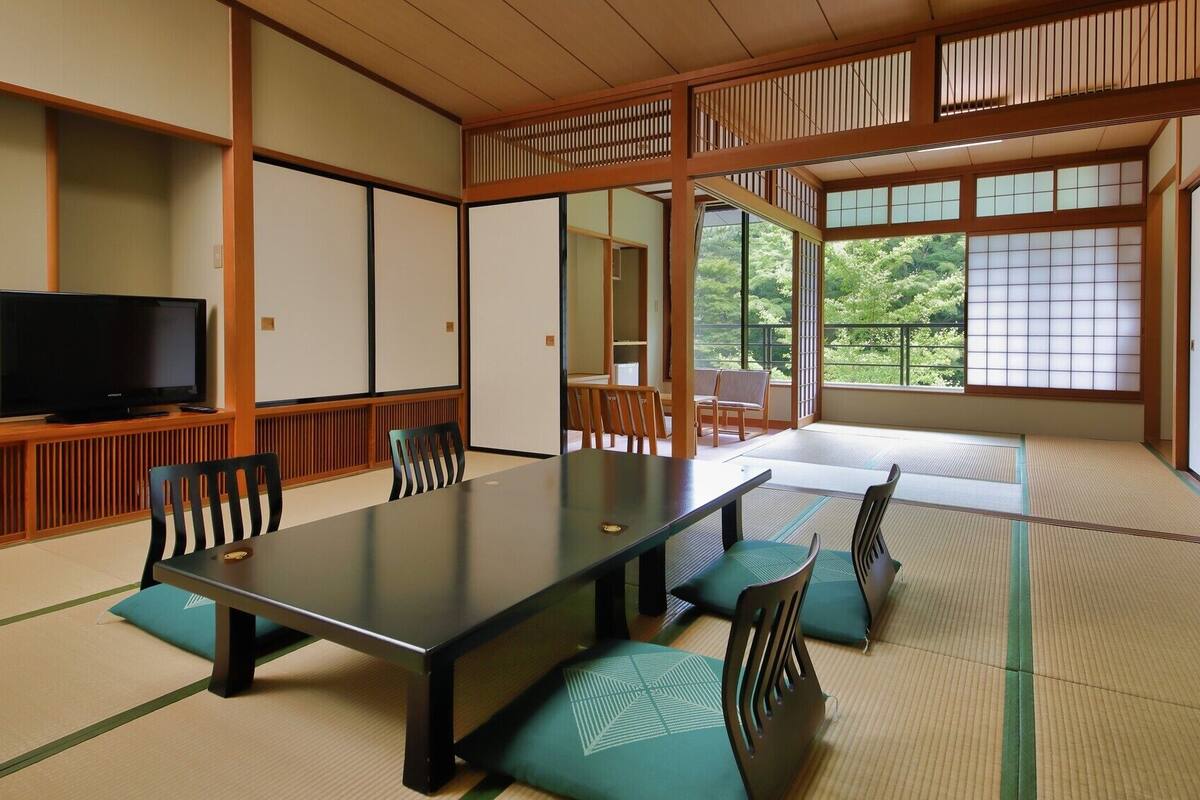 A traditional Japanese-style room with tatami flooring, a low table, and a television.