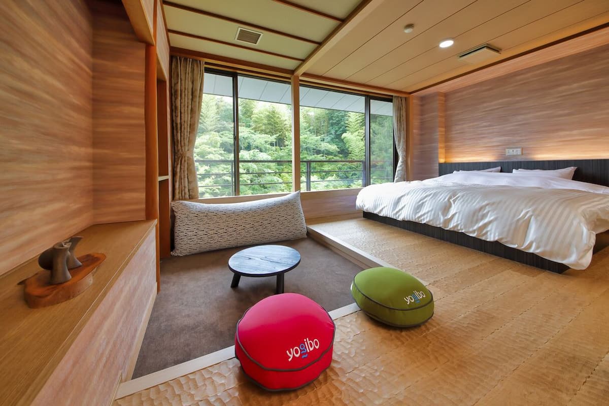 A modern hotel room with a large bed, a small round table, and two bean bags.