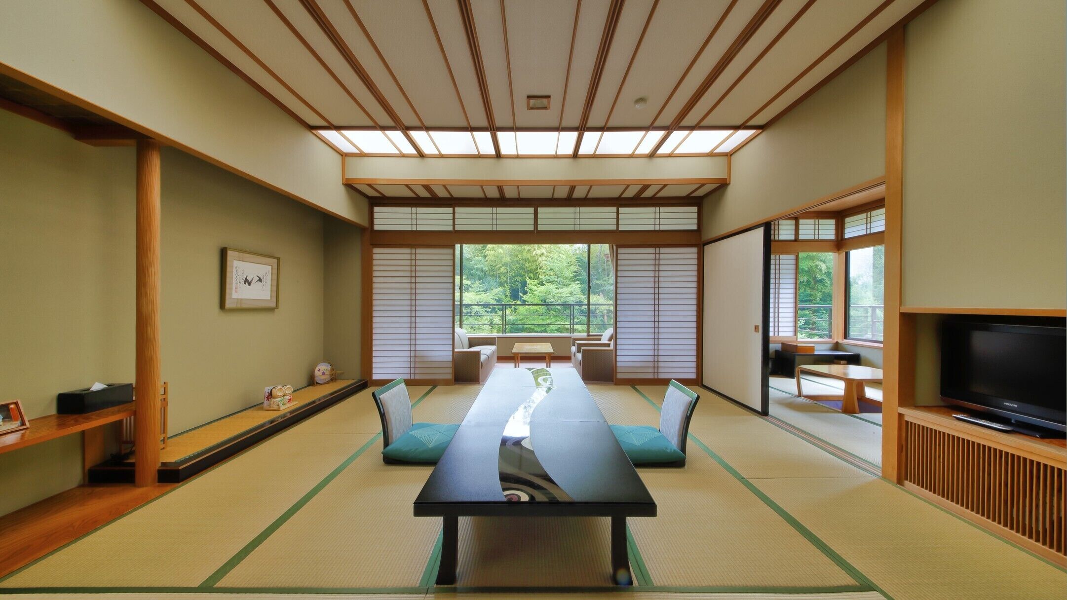 A traditional Japanese room with tatami flooring, a low table, seating, and a TV.