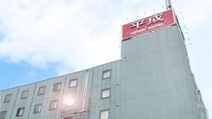 A hotel with a prominent red sign at the top, multiple floors, and a large entrance with a glass facade. - Heisei Hotel (Chikusei)