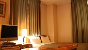 A hotel room with a bed, a television, a desk, and a chair. - Heisei Hotel (Chikusei)