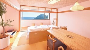A modern bedroom with a large window, a bed, a desk, and a potted plant.