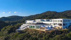 A modern multi-story building with large windows, a rooftop terrace, and a pool area. - Ashizuri Thermae (Tosashimizu)