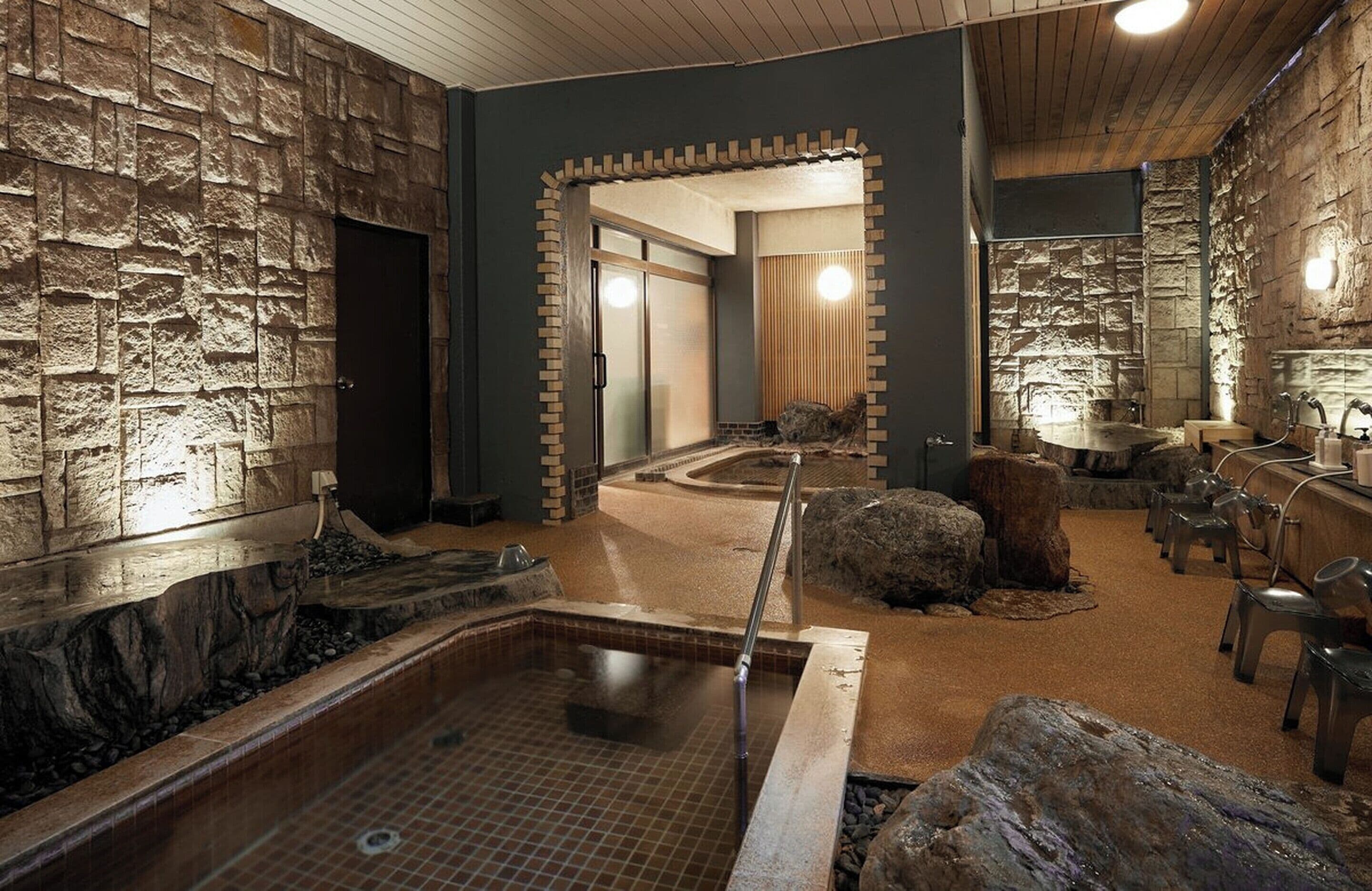 A spa area with a stone wall, a hot tub, and a wooden table with chairs.