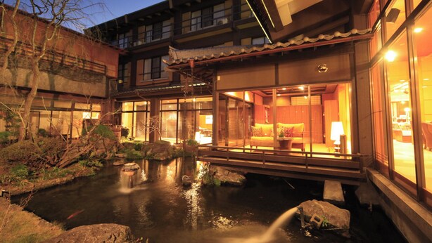 A traditional Japanese-style building with a koi pond, wooden walkways, and a view of the interior. - Itoyanagi Koyado Yuwa (Fuefuki)