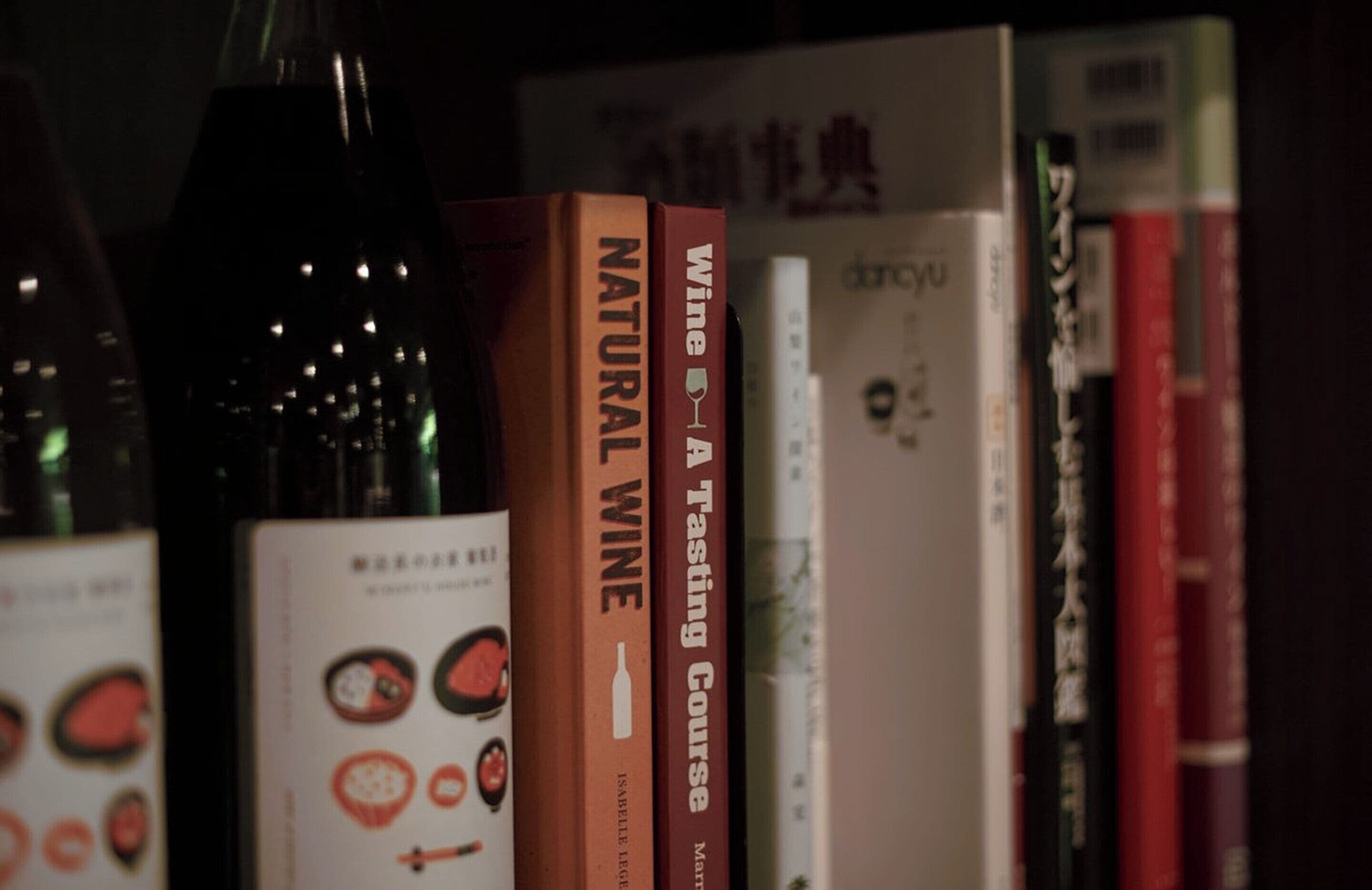 A bookshelf with books and a wine bottle.