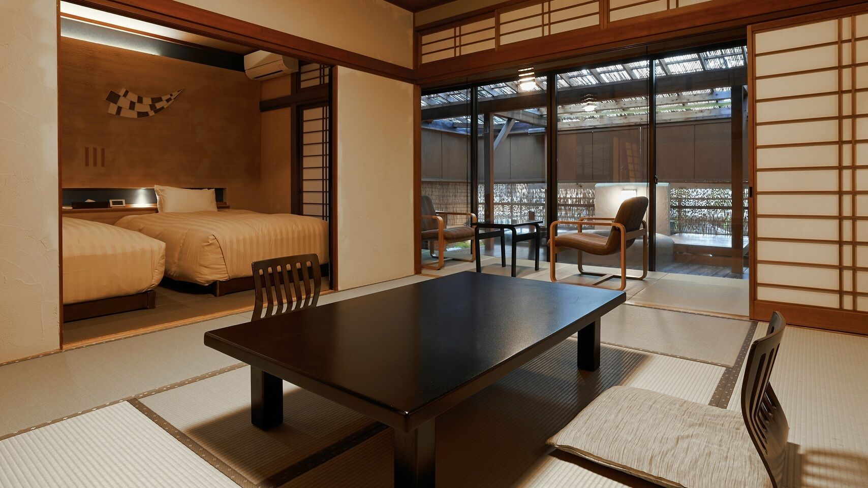 A traditional Japanese-style room with tatami flooring, a low table, and a bed with a futon.