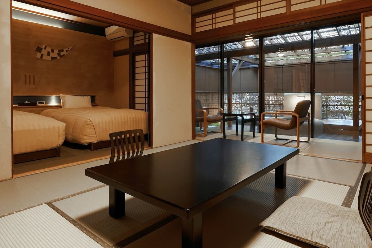 A traditional Japanese-style room with tatami flooring, a low table, and a bed with a futon.