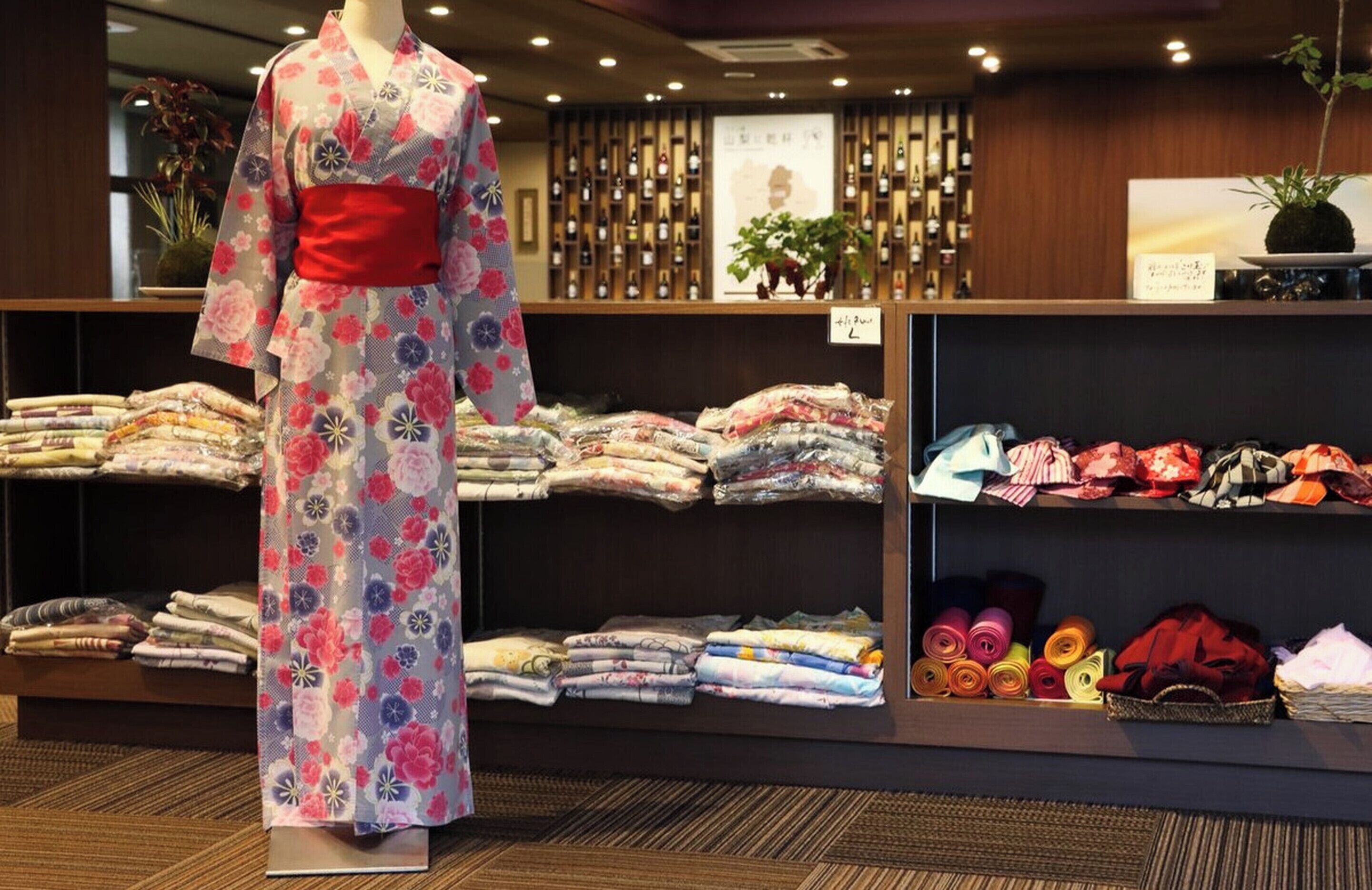 Une exposition de kimonos japonais traditionnels, avec un mannequin portant un kimono à motifs floraux.