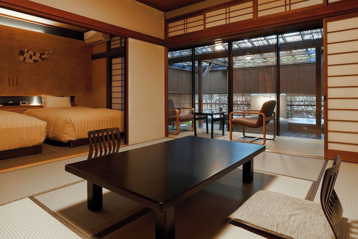 A traditional Japanese-style room with tatami flooring, a low table, and two beds.