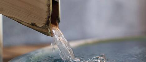 A wooden structure with water flowing into a blue basin.