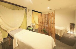 A room with two beds covered in white linens, a bamboo partition, a small table with a kettle, and a wall-mounted shelf with toiletries. - Itoyanagi Koyado Yuwa (Fuefuki)