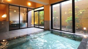 A modern indoor swimming pool with glass walls, a hot tub, and a view of greenery outside. - Itoyanagi Koyado Yuwa (Fuefuki)