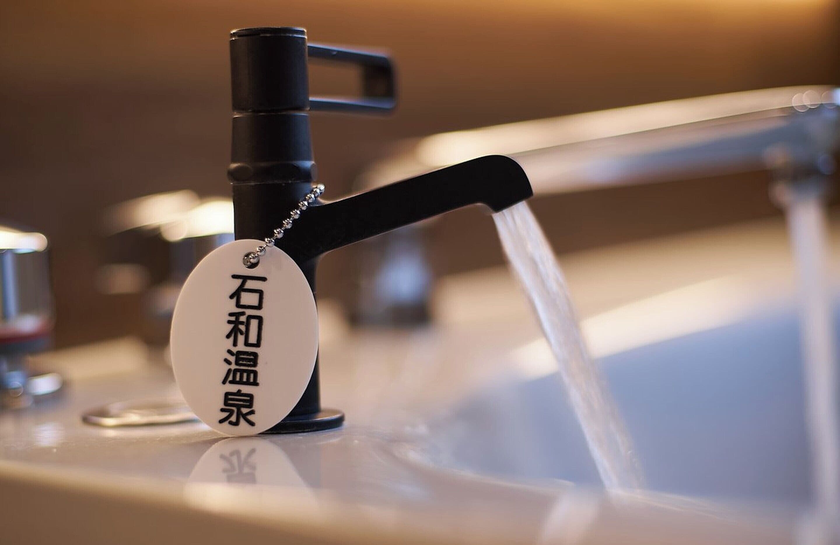 A faucet with a tag that reads "石和温泉" (Shikawa Onsen).